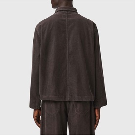 Model wearing All Saints dark brown corduroy jacket, rear view, styled with matching corduroy trousers.