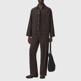 Model wearing All Saints dark brown jacket and matching wide-leg trousers, styled with a black tote bag.