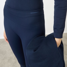 Model wearing Adanola navy blue seamless leggings with wide waistband, styled with matching long-sleeve top and wide-leg trousers