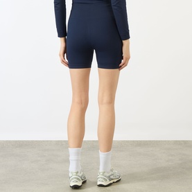 Model wearing Adanola navy blue cycling shorts with matching long-sleeve top, white socks and trainers, rear view.