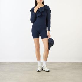 Model wearing Adanola navy blue cycling shorts with matching ribbed ruffle top and white trainers.