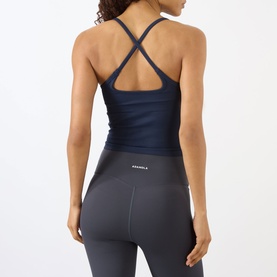 Model wearing Adanola navy blue tank top with cross-back straps, styled with grey leggings, back view
