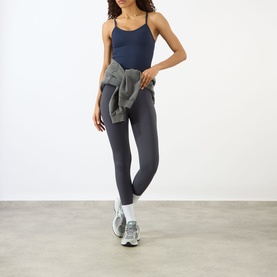 Model wearing Adanola navy blue tank top with matching leggings, grey zip-up tied at waist, white trainers.