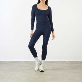 Model wearing Adanola navy blue long-sleeve scoop-neck top with matching leggings and white chunky trainers.