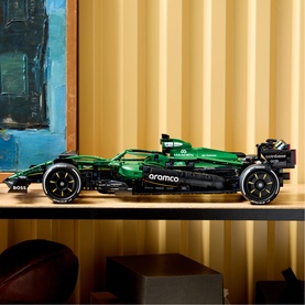 Lego Technic Aston Martin Aramco F1 car model in green with detailed livery, displayed on a wooden surface against a gold backdrop