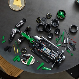 Lego Technic Formula E racing car build laid out on dark surface showing assembled car body, tyres, and green accent pieces