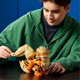 Child building Lego Pok&eacute;mon Charizard construction set, shown mid-build on a dark surface, wearing a green hoodie
