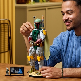 Model with Lego Star Wars Boba Fett buildable figure in multi-coloured bricks, displayed on a table with small scene base