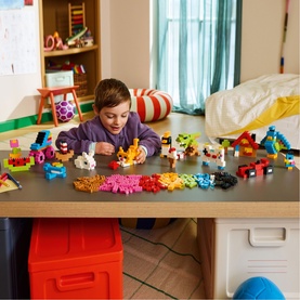 Child building with Lego Classic Creative Colourful Bricks Set, 820 multicoloured pieces spread across a table in a bright playroom