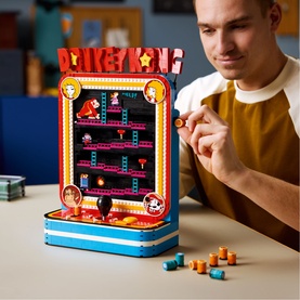 Lego Super Mario Donkey Kong arcade cabinet build displayed on table, model assembling in background, multi-coloured brick set