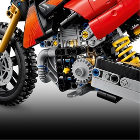 Lego Technic motorcycle toy in red and grey with detailed engine, yellow suspension, and knobbed tyres visible in close-up build shot