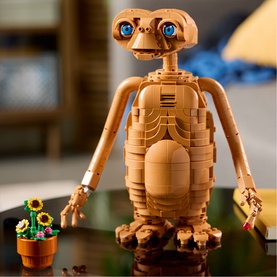 LEGO Ideas E.T. the Extra-Terrestrial buildable figure in tan, posed with small sunflower pot accessory on reflective surface