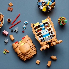 Lego Ideas multi-coloured construction toy set with tan barrel builds and scattered bricks displayed on grey surface