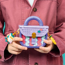 Model with Lego Creator Art Fashion Bag with Storage in multi-coloured bricks, purple handbag design with gold clasp and keychain charm