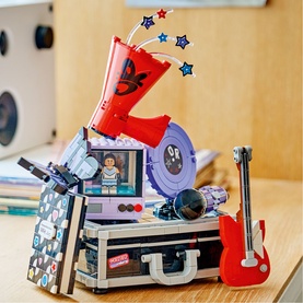 Lego Editions Music toy set featuring a buildable stage, guitar, red microphone, and mini figure, displayed on a desk