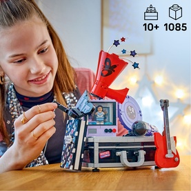 Girl playing with Lego Music Edition set featuring microphone, guitar, and stage scene. 1085 pieces, ages 10+