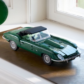 Lego Icons green classic Jaguar E-Type convertible model car, displayed on a wooden surface near a window