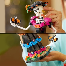 Lego Ideas Day of the Dead skeleton figure toy in multi-colour, held by hands, showing floral skirt and orange butterfly details