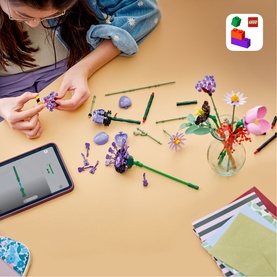 Child assembling Lego Botanical multi-coloured flower set at a table, with completed floral builds and building instructions visible nearby
