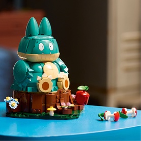 Lego Pok&eacute;mon Munchlax buildable figure in teal, seated on green base with floral details and small accessory figures alongside