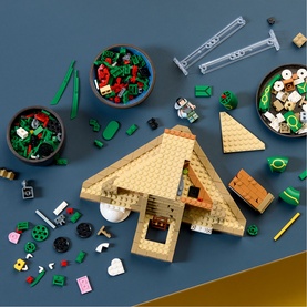 Lego Pok&eacute;mon set 3814 with tan triangular structure, scattered multicoloured bricks, green foliage pieces, and small figurines on blue surface