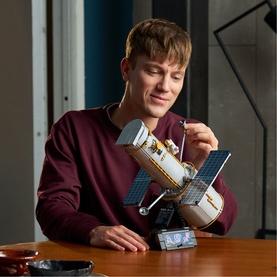Model with Lego Icons Hubble Space Telescope set, detailed multi-coloured build with solar panels, shown on a wooden table