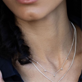 Model with Juvi silver layered chain necklaces featuring delicate crystal stations, worn close to the neck
