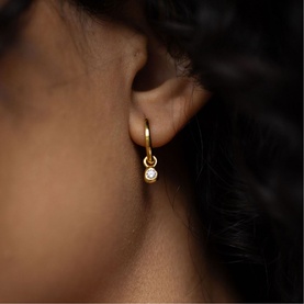 Model with Juvi gold hoop earring featuring a bezel-set crystal drop pendant
