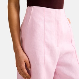 Model wearing Forever New Candy Hearts pink high-waisted tailored trousers with front seam detail, styled with a dark burgundy top.