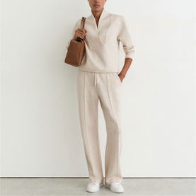 Model wearing Reiss neutral marl knit half-zip top and wide-leg trousers, styled with a tan leather tote bag.