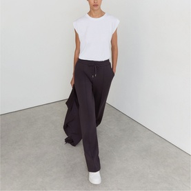 Model wearing Reiss grape burgundy wide-leg trousers with drawstring waist, styled with a white sleeveless top and white trainers.