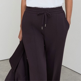 Model wearing Reiss grape burgundy wide-leg drawstring trousers, styled with a white top and matching jacket