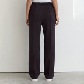 Model wearing Reiss grape burgundy wide-leg tailored trousers, rear view, high-rise waistband, full-length straight cut.