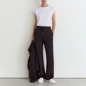 Model wearing Reiss grape burgundy wide-leg trousers with drawstring waist, styled with white sleeveless top and matching jacket.