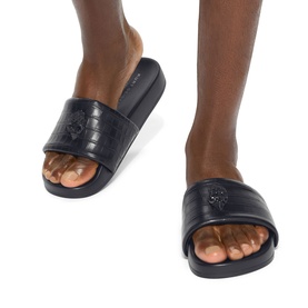 Model wearing Kurt Geiger London black leather slides with embossed logo strap and flatform sole