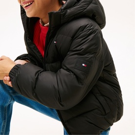 Model wearing Tommy Hilfiger black hooded puffer jacket, styled with red top and blue jeans