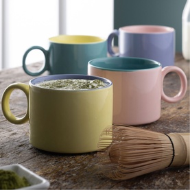 Belleek Hoopla Mug Set of Four in multi pastel shades with round statement handles, styled with matcha and whisk on rustic surface
