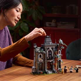 Model with Lego Icons haunted house building set, shown assembled on a table with minifigures, in a lifestyle setting