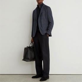 Model wearing Reiss blue check blazer with black trousers and turtleneck, carrying a black leather tote bag.