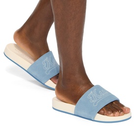 Model wearing Kurt Geiger London blue suede slides with embroidered logo strap and cream flatform sole