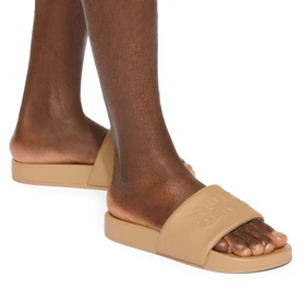 Model wearing Kurt Geiger London white men's slider sandals with embossed strap and flatform sole
