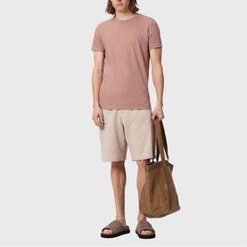 Model wearing pink crew neck T-shirt and beige shorts, carrying large brown tote bag, styled with brown sandals