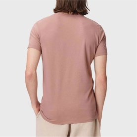 Model wearing dusty pink short-sleeve crew neck T-shirt, back view, styled with light beige trousers