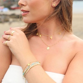 Model with Juvi Ammonite Shell Earrings in gold, 18ct gold plated brass shell studs, styled with layered gold necklaces and bracelet