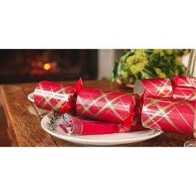 Celebration Crackers 12 Pack Red Plaid Christmas Crackers with gold foil details and ribbon ties, styled on a plate beside a fireplace