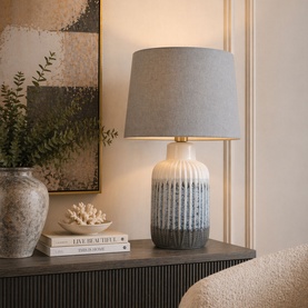 Mindy Browne Hallie Textured Table Lamp in blue grey cream, ceramic base with ribbed detail, brass neck, and grey linen shade, styled on a sideboard.