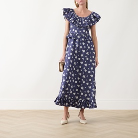 Model wearing Queens of Archive Devon Prairie Floral Dress in Prairie Rose Blue with frill neck and hem, styled with cream heels and a gold clutch