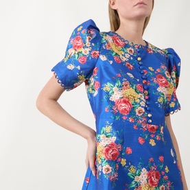 Model wearing Queens of Archive Margot Dutch Floral Mini Dress in Dutch Floral Cobalt with puff sleeves, button bodice, and rouleau trim detail.