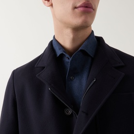 Model wearing Corneliani Stand-Collar Wool Jacket in navy, styled over a dark denim shirt, showing notched lapel and button fastening detail.