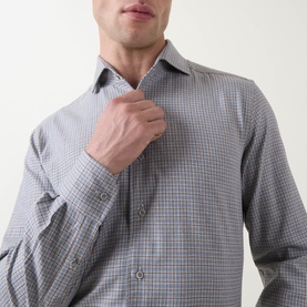 Model wearing grey micro-check long-sleeve shirt with spread collar, adjusting front placket
